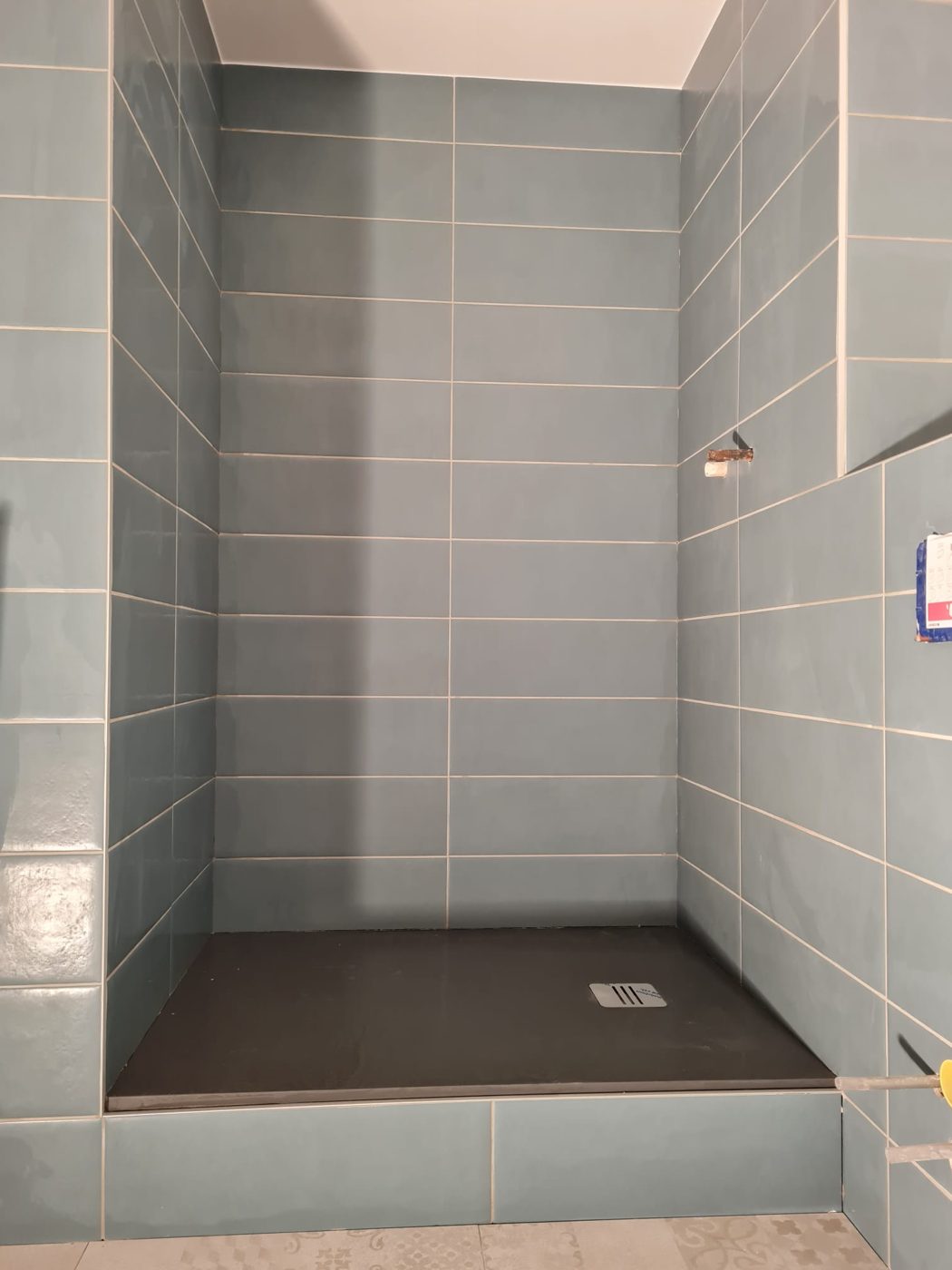 Douche terminée avec carrelage bleu et receveur extra-plat